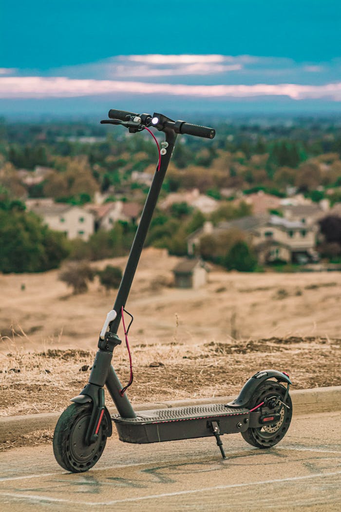 A modern electric scooter parked on an urban overlook with a scenic city backdrop, suggesting eco-friendly urban transportation.